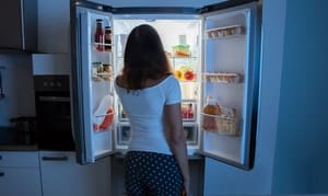 Jeune femme cherchant dans le réfrigérateur